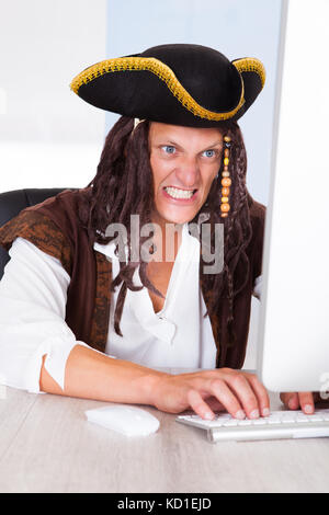 Portrait Of A Angry Pirate Clenching His Teeth Using Computer Stock Photo