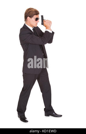 Young Man In Black Suit Holding A Gun On White Background Stock Photo