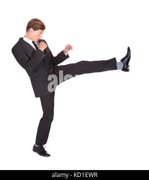 Young Man In Black Suit Kicking On White Background Stock Photo