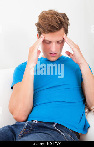 Portrait Of A Young Man Holding His Temple While Suffering From Headache Stock Photo