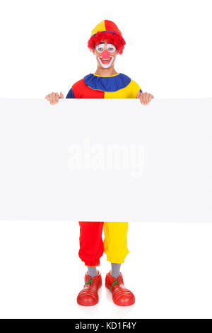 Portrait Of A Happy Joker Holding Blank Placard Over White Background Stock Photo