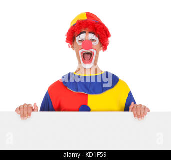 Portrait Of A Happy Joker Holding Blank Placard Over White Background Stock Photo