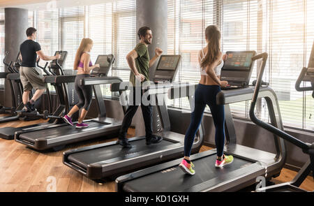 Group of four people running on treadmills in fitness gym Stock Photo