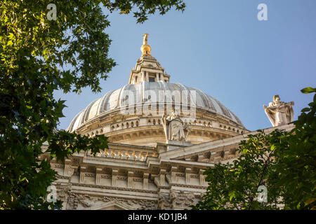 St. Paul's Cathedral dome viewed through trees and leaves in the churchyard garden. City of London, UK Stock Photo
