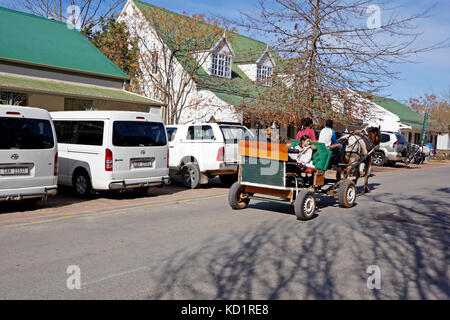 Visitors having a drive in a donkey cart in the main road of the picturesque village of Greyton in the Western Province of South Africa. Stock Photo