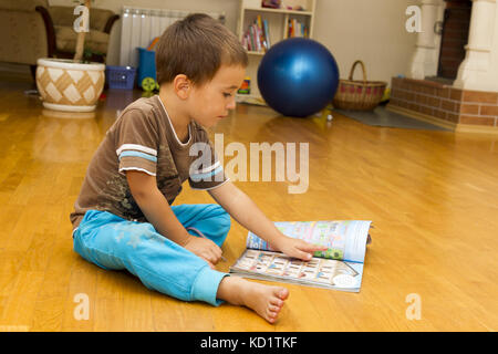 Little boy is sitting on the floor with a book Stock Photo