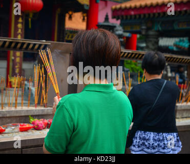 Hong Kong - Mar 30, 2017. Prayers at Wong Tai Sin Temple in Hong Kong, China. Wong Tai Sin Temple is a well known shrine and major tourist attraction  Stock Photo