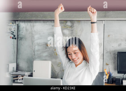 Asian businesswoman raise arm up stretching in front of desk from work on notebook screen in office,Office lifestyle concept Stock Photo