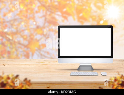 Computer desktop with keyboard and mouse on wood table with blur maple leaf with sunlight and blurred leaves at foreground,Autumn Mock up for display  Stock Photo