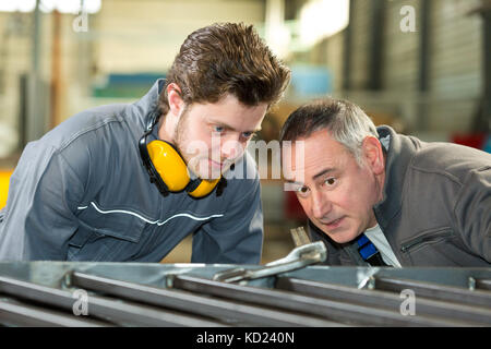 apprentice and teacher working with metal bars in a factory Stock Photo