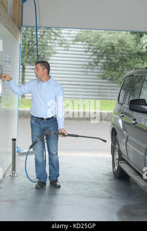 person paying coins to self service automatic car cleaning machine Stock Photo