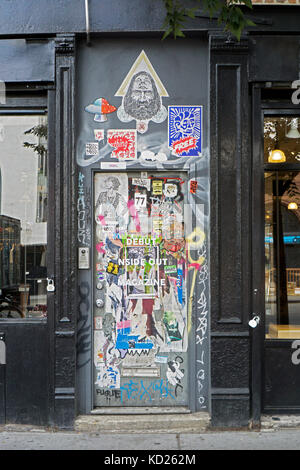 A doorway on Houston Street in the East Village with graffiti, stickers and tagging. Manhattan, New York City.