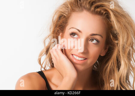 Beautiful young woman hand touching face looking up smiling against a white background Stock Photo