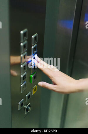 Woman pressing button inside elevator. Stock Photo