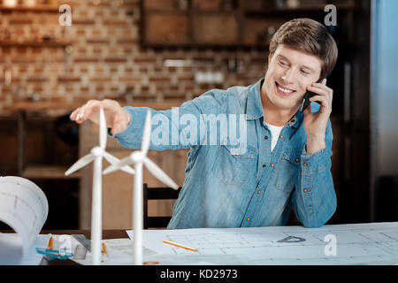 Young engineer making phone call while working on blueprint Stock Photo