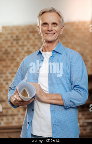 Joyful senior engineer smiling and holding blueprint Stock Photo