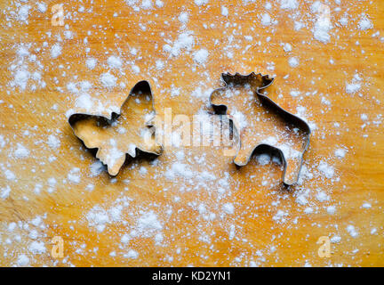 Metal forms (molds, cutters) for ginger cookies in the shape of elk or moose and butterflies on wooden board, sprinkled with baking flour. Stock Photo