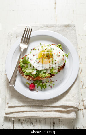 Avocado toast with radish, fried egg and micro greens Stock Photo