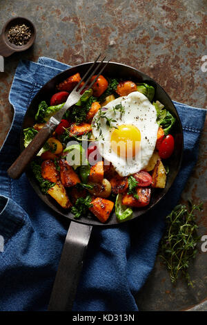 Breakfast hash with fried egg in cast iron skillet Stock Photo