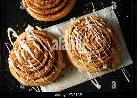 Cinnamon Rolls drizzled with Icing on wax paper Stock Photo