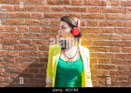 Woman standing next to red brickwall Stock Photo
