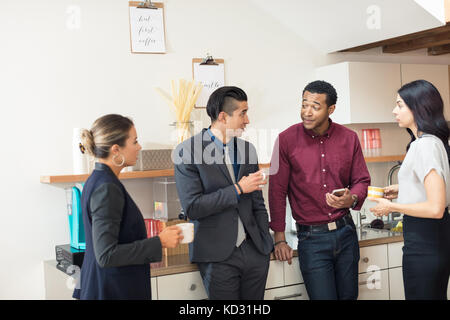 Businesswomen and men having informal meeting in office kitchen Stock Photo