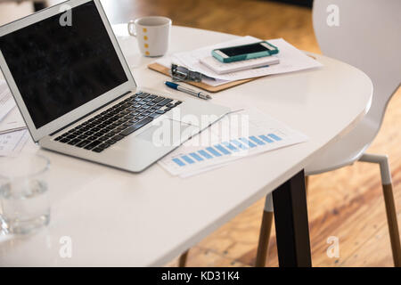 Laptop, bar chart and smartphone on office desk Stock Photo