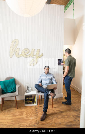 Cool young businessmen in creative office using digital tablet and laptop Stock Photo