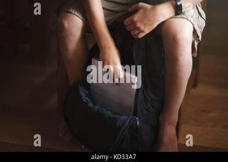 Boy packing backpack with school stationery supplies Stock Photo