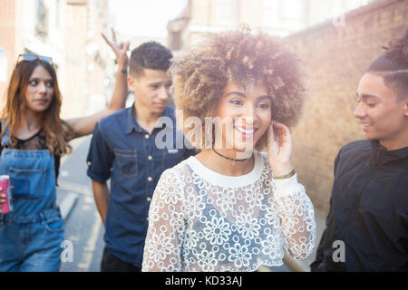 Four young friends walking outdoors, smiling Stock Photo
