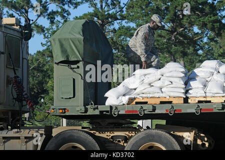 U.S. Army Soldiers from the 1052nd Transportation Company, South Carolina National Guard unload sandbags at the 8 Oaks Park near Georgetown, S.C. on Oct. 7, 2015. The sandbags were delivered in response to widespread flooding in the area as a result of heavy rain. The South Carolina National Guard partnered with federal, state and local emergency management agencies and first responders to provide assistance. (U.S. Army National Guard photo by Sgt. Kevin Pickering/Released) Stock Photo