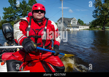 A swift water rescue firefighter from Columbia, Tenn., paddles through floodwater while conducting wellness checks on the residents of Brown's Ferry, Georgetown, S.C., Oct. 11, 2015. The South Carolina National Guard has been activated to support state and county emergency management agencies and local first responders as historic flooding impacts counties statewide. Currently, more than 3,000 South Carolina National Guard members have been activated in response to the floods. (U.S. Air National Guard photo by Tech. Sgt. Jorge Intriago/Released) Stock Photo