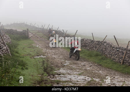 Motorcyclists on a misty day on Cam High Road, an ancient Roman route, in the Yorkshire Dales. The green lane is a byway open to all traffic Stock Photo