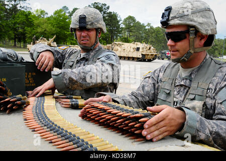 U.S. Army Staff Sgt. Russell Williams and Capt. David House, assigned to Charlie Company, 1-118th Combined Arms Battalion, South Carolina Army National Guard, prepares .50-caliber ammo for gunnery exercises on the ranges of Fort Stewart, Ga., April 14, 2014 as part of their annual training. Annual training for C Co. began with crewmembers receiving 14 new M1A1SA Abrams Main Battle Tanks where they received classroom and hands-on training for the new equipment. Annual training for C Co. concluded with Soldiers loading several of their M1s onto U.S. Air Force C-17 transport planes for transporta Stock Photo