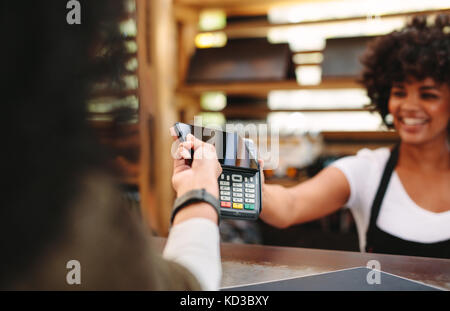 Customer making wireless or contactless payment using smartphone. Cashier accepting payment over nfc technology. Stock Photo