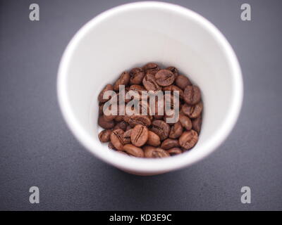 Shanghai, China - 14 October 2016: Coffee beans in a paper cup on a grey table Stock Photo
