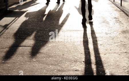 Blurry long shadows and silhouettes of people on the city sidewalk Stock Photo