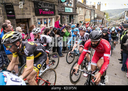 Riders in the Tour de Yorkshire ascend Main Street in Haworth, West Yorkshire Stock Photo