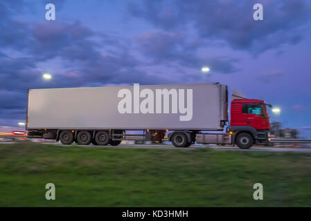 A large modern truck  is driving along the highway in the night. Stock Photo