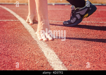Runner in start position. Hands on starting line. Sport running in ...