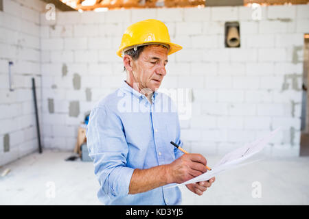 Senior architect or civil engineer at the construction site with blueprints, controlling issues at the construction site. Stock Photo