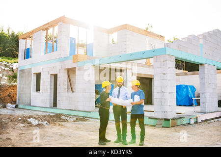 Architect, civil engineer and worker looking at plans and blueprints, discussing issues at the construction site. Stock Photo