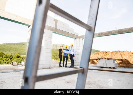 Architect, civil engineer and worker looking at plans and blueprints, discussing issues at the construction site. Stock Photo