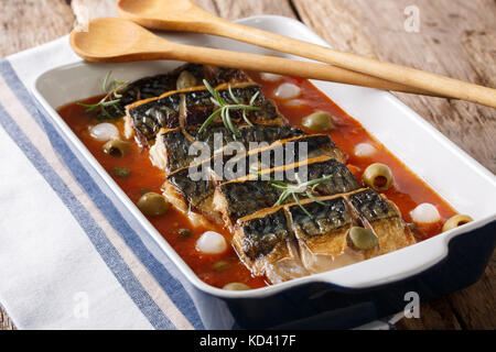 Delicious baked mackerel with capers and olives in tomato sauce close-up on a table in a baking dish. horizontal Stock Photo