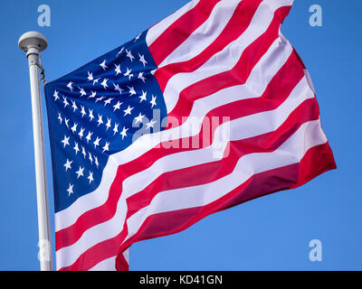 Stars & Stripes American Flag in close-up, fluttering in breeze with sunny blue sky behind USA Stock Photo