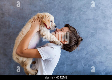 Portrait of teen boy with golden retriever by the wall Stock Photo