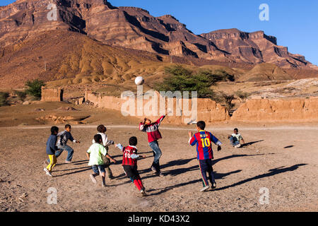 MOROCCO-DEC 27, 2012: Local boys play with a soccer ball on a dirt field. Location: Draa Valley village. Soccer is the #1 sport among youth in Morocco Stock Photo