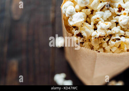 Popcorn in paper bio ecological bag on wooden background. Copy space, close up Stock Photo