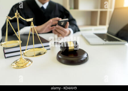 Judge use computer mobile phone in the office with Scales gavel hammer in office Stock Photo