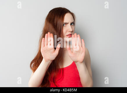 A frightened annoyed young woman holds her hands in front of her making stop sign, defending herself from someone or pushing someone away Stock Photo